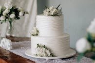 Beautiful two-tier white wedding cake adorned with fresh flowers on a rustic wooden table.
